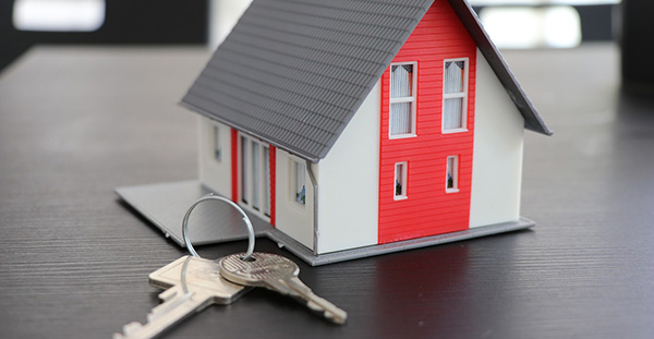 Une petite maquette de maison posée sur une table à côté d'un trousseau de clé.